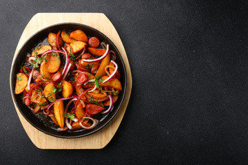 frying pan with potatoes meat and onion on black concrete background. mexican food concept. potatoes fried in a pan