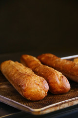 fresh baguette bread on a baking sheet and dark background