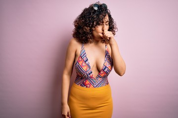 Young beautiful arab woman on vacation wearing swimsuit and sunglasses over pink background feeling unwell and coughing as symptom for cold or bronchitis. Health care concept.