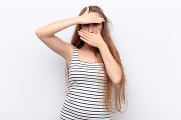 yound blonde woman covering face with both hands saying no to the camera! refusing pictures or...