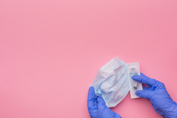 Hands in latex gloves, a syringe and a disposable protective mask on a pink background. Vaccination concept. Copy space.