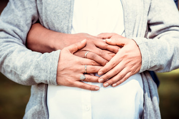 Hands of mature man and his pregnant mature wife touching her belly
