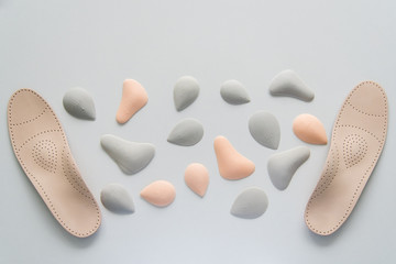 A pair of leather orthopedic insoles surrounded by components. Pelots for unloading the cross arch of different shapes and sizes. Choice.