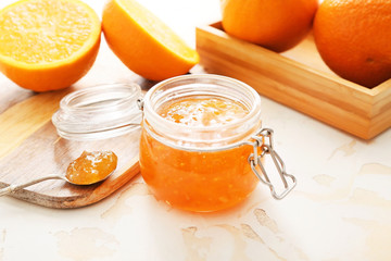 Jar of orange jam on white table