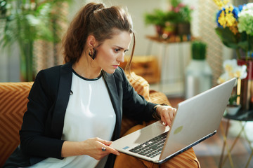 concentrated stylish woman editing while sitting on sofa