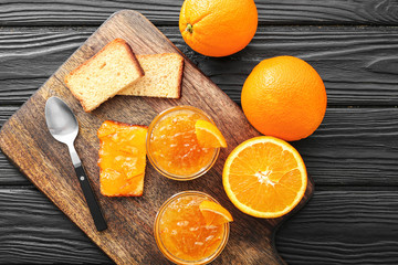 Fototapeta na wymiar Bowls of orange jam with slices of bread on table