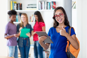 Cheering nerdy female student with tablet computer with group of multi ethnic college students