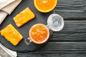 Jar of orange jam with slices of bread on table
