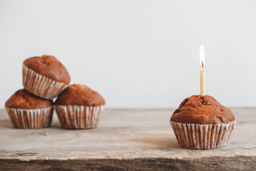 Chocolate cupcakes with candle on wooden table. Copy, empty space for text