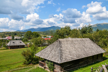 Rural landscape with ancient wooden houses on a green hill in the mountain village Kolochava, Transcarpathia, Ukraine