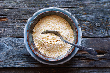 Useful chickpea flour in a ceramic bowl with spoon on a wooden table Healthy vegan ingredient 