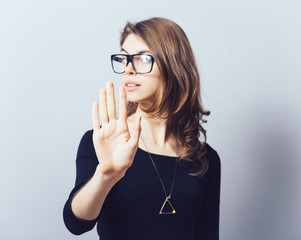 A woman shows a stop on a grey background