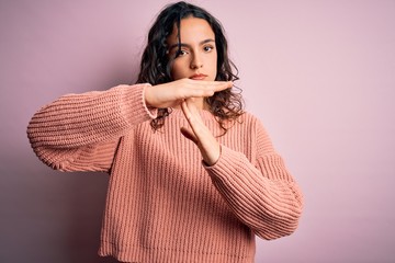 Young beautiful woman with curly hair wearing casual sweater over isolated pink background Doing...