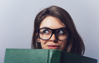 Young beautiful Girl with glasses reading a  big green book - 338542014
