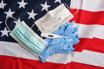 Used surgical protective masks, gloves, digital thermometer on american flag background. Covid-19 quarantine. Flat lay, top view
