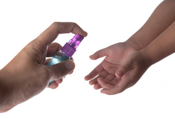 Using alcohol spray antivirus sanitizer on child's hands on white background