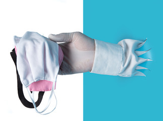Hand with medical gloves hold masks through the torn blue plastic isolated on white background
