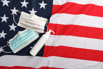 Used protective masks and sanitizer pump bottle on american flag background. Covid-19 quarantine. Flat lay, top view, copy space