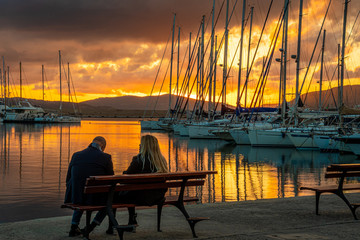 uno sguardo al tramonto 01 -  due persone sedute su di una panchina guardano  il porto nella...