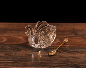 Crystal swans teaspoon on a wooden table.