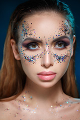 Beauty portrait of a beautiful sexy girl with bright makeup and sparkles in the shape of a mask on her face.