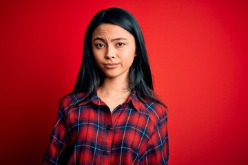 Fototapeta premium Young beautiful chinese woman wearing casual shirt over isolated red background looking sleepy and tired, exhausted for fatigue and hangover, lazy eyes in the morning.