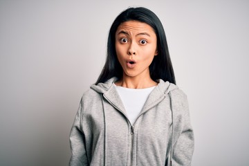 Young beautiful chinese sporty woman wearing sweatshirt over isolated white background afraid and shocked with surprise expression, fear and excited face.