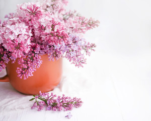 Bouquet of lilacs in a vase on a table on a white background, copy space, soft focus	