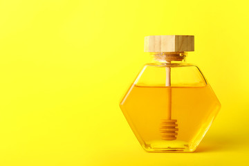 Jar of sweet honey on color background