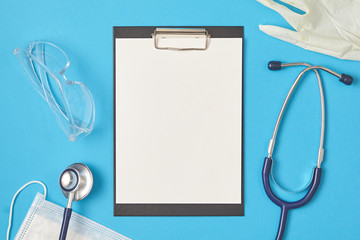 Blank paper sheet and medical supplies on blue background