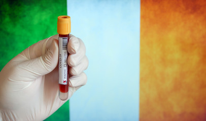COVID-19 Pandemic Coronavirus concept ; Close-up of a Positive COVID-19 blood test sample tube with Flag of Ireland at background. Blood testing for diagnosis new Corona virus infection.