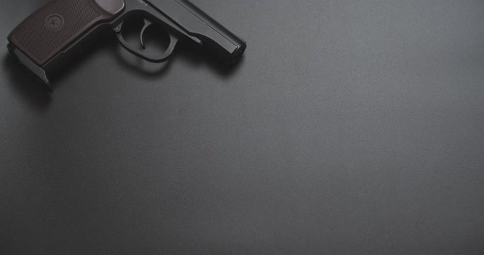 gun on a black background and falling a bundle of dollars in left side