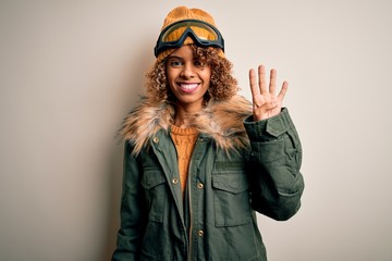 Young african american skier woman with curly hair wearing snow sportswear and ski goggles showing and pointing up with fingers number four while smiling confident and happy.
