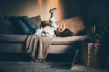 Bored woman in self isolation laying on the sofa. Woman in quarantine for coronavirus working from...