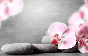 Spa stones and pink orchid on the grey background.