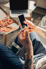 Scrolling news. Man studying at home during online courses, smart school. Getting classes or profession while isolated, quarantine against coronavirus spreading. Using laptop, smartphone, headphones.