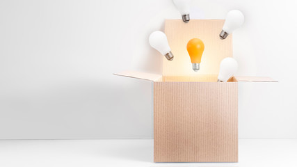 White and orange energy-saving light bulbs flying out of the open carton box on white background....