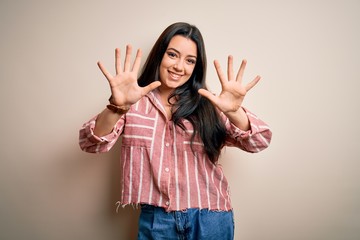Young brunette woman wearing casual striped shirt over isolated background showing and pointing up...