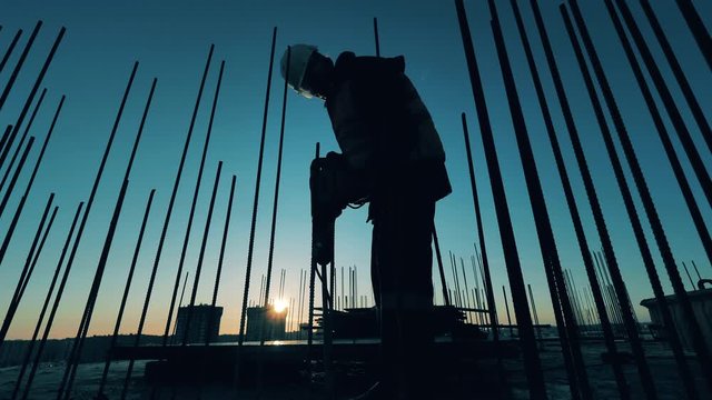 Male constructor is using a jackhammer to break concrete