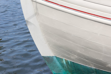 Bow of an old wooden boat, white green and red paint, copy space, horizontal aspect