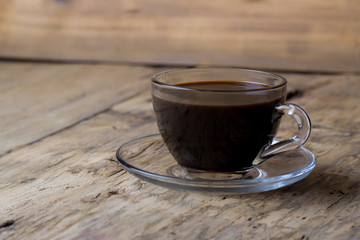 Coffee in a transparent glass cup on a wooden table
