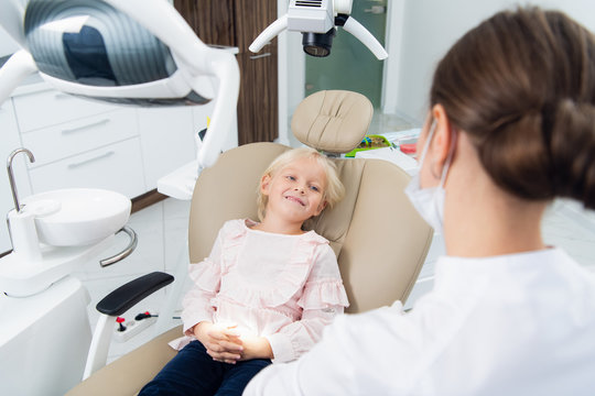 Image of a little girl in a dentist's chair having her teeth checked by a doctor
