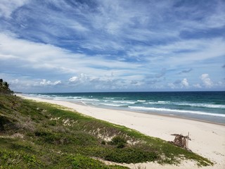 Fototapeta na wymiar praia, mar, areia, vegetação rasteira, céu azul, nuvens
