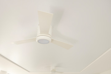 An overhead LED luminaire combined with a white ceiling fan on a white ceiling.