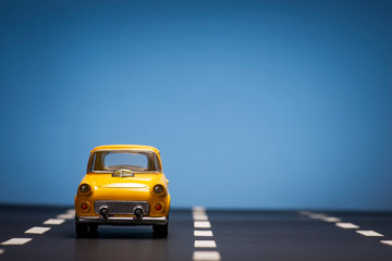 Fototapeta na wymiar Yellow toy car on a blue background.