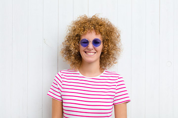 young pretty woman looking happy and friendly, smiling and winking an eye at you with a positive...