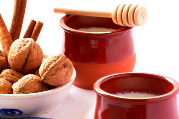 Natural goat milk curd with cinnamon, walnuts and honey in clay glass and wooden spoon