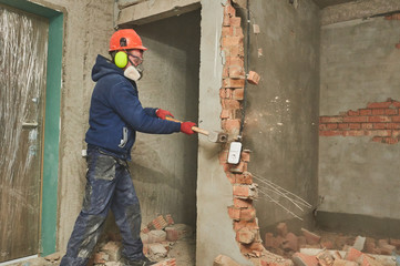 demolition work and rearrangement. worker with sledgehammer destroying wall