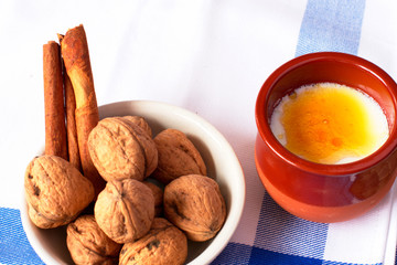 Natural goat milk curd with cinnamon, walnuts and honey in clay glass and wooden spoon