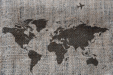 Fototapeta na wymiar A map of the world drawn on a rough gray cloth, the plane flies over the continents.